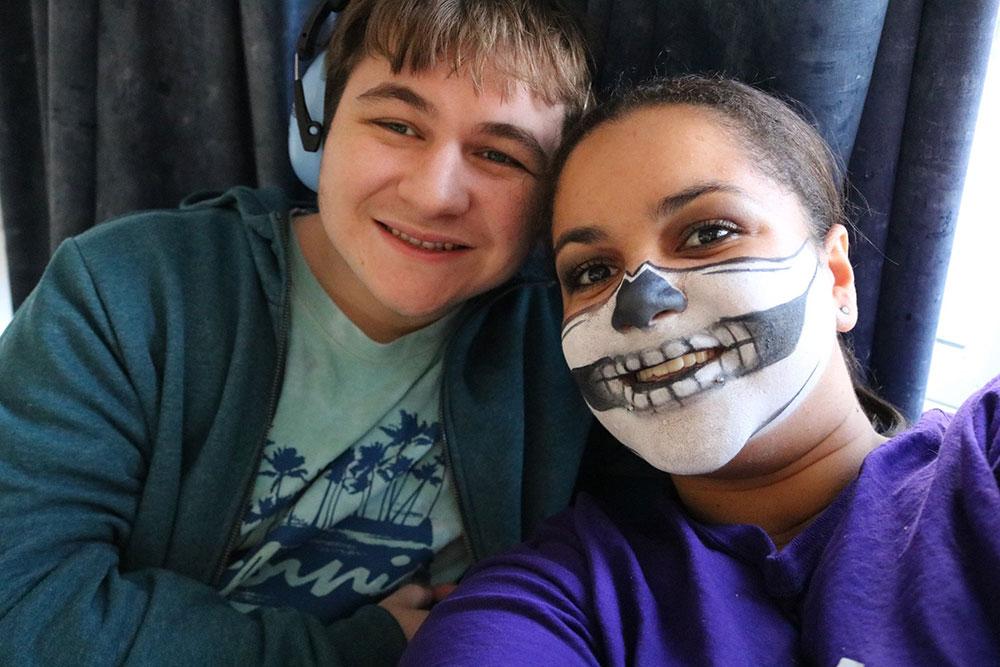 Play Worker with face painted smiling with young person