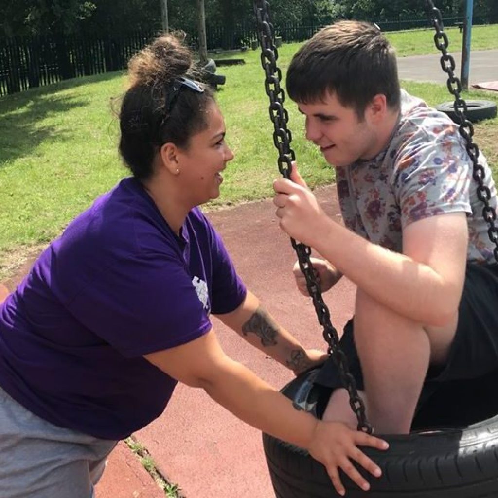 Play Worker pushing young person on tyre swing