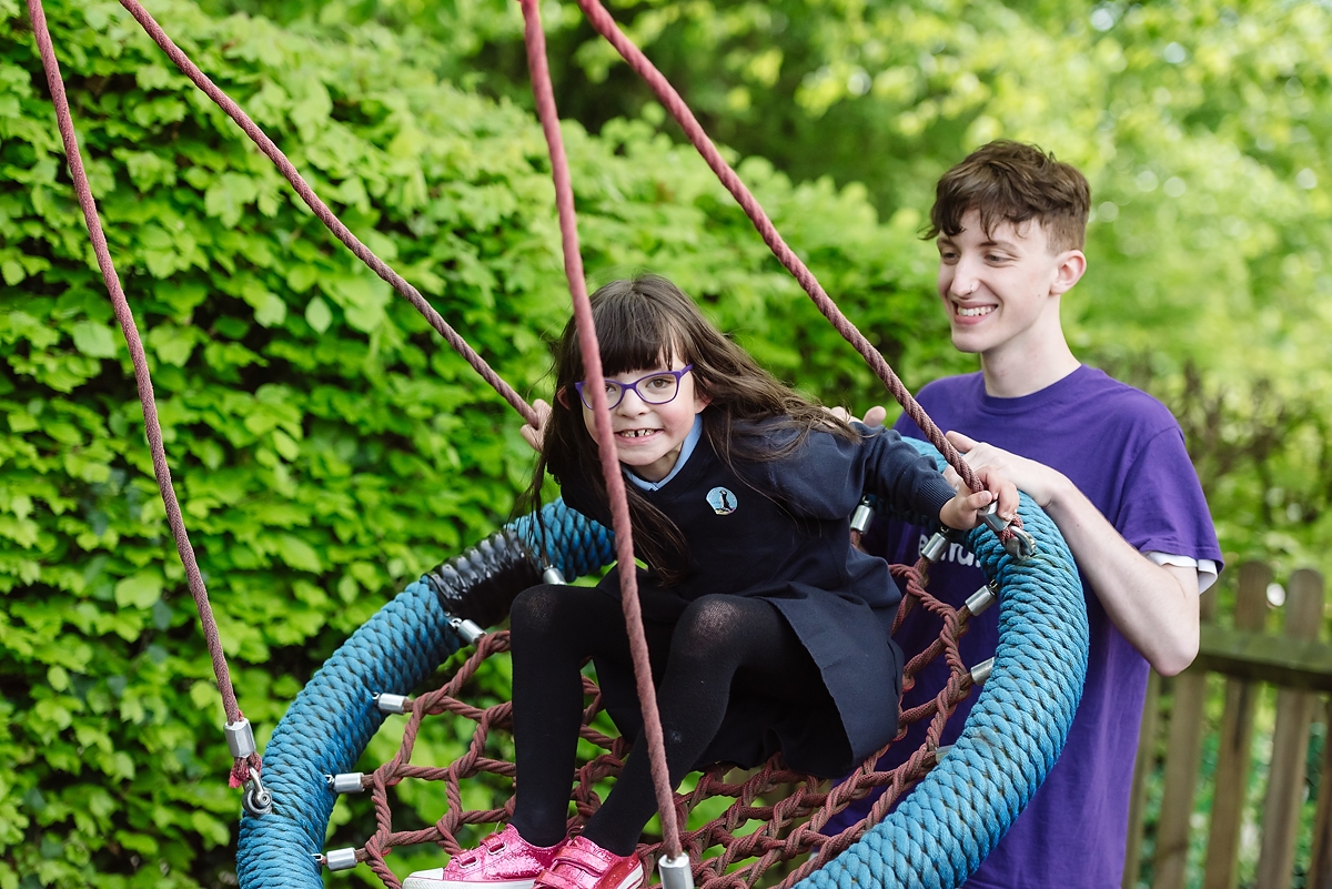 Play Worker pushing young person on swing